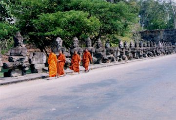 網引きをする神々の石像前を歩く僧侶