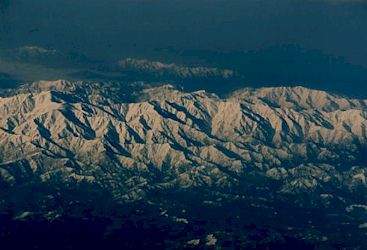 機内窓より見える朝日に浮かぶ雪化粧の山々−1