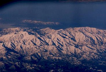 機内窓より見える朝日に浮かぶ雪化粧の山々−2