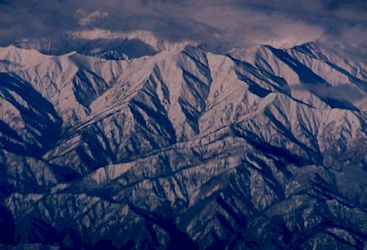 機内窓より見える朝日に浮かぶ雪化粧の山々−3